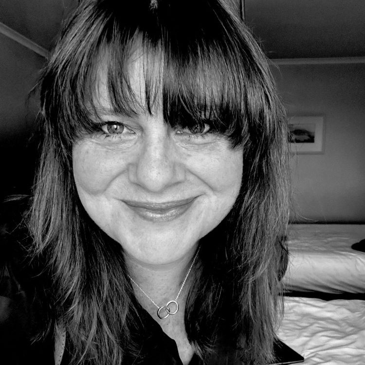 Black and white image of Tess Crawley, psychologist and business coach, smiling towards camera.